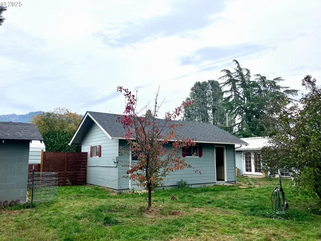 a front view of a house with a garden and trees
