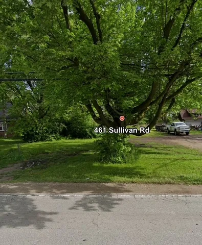a sign that is sitting in front of a house with a big yard
