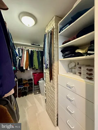 a view of walk in closet with clothes and shoes