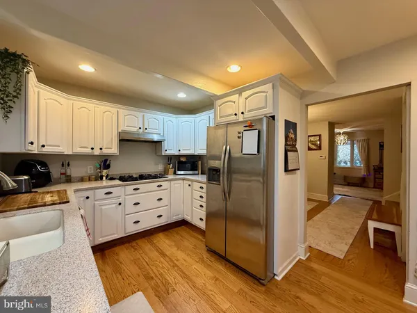 a kitchen with stainless steel appliances granite countertop a refrigerator a stove and white cabinets with wooden floor