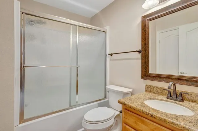 a bathroom with a granite countertop sink toilet and shower