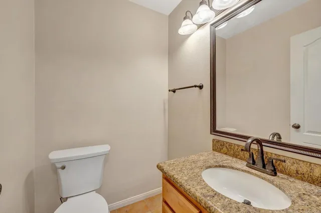 a bathroom with a granite countertop toilet a sink and a mirror
