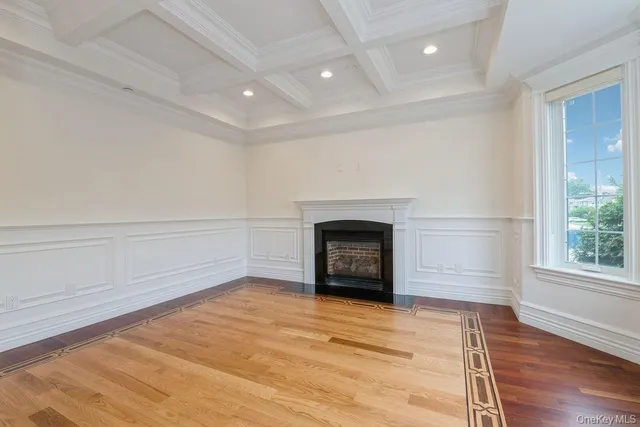 an empty room with wooden floor a fireplace and windows