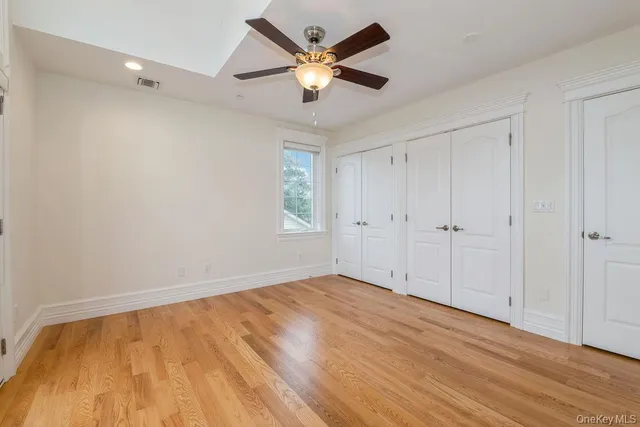 an empty room with wooden floor fan and windows