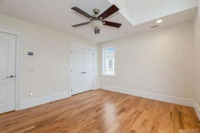 an empty room with wooden floor a ceiling fan and windows