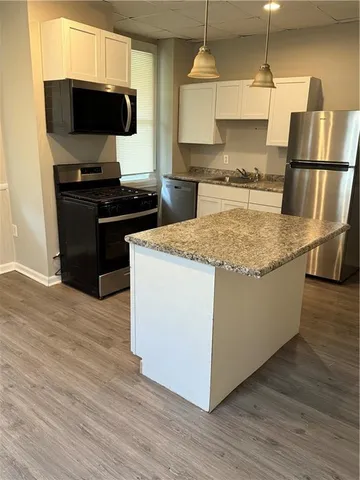 a kitchen with stainless steel appliances granite countertop a sink a stove and a wooden floor