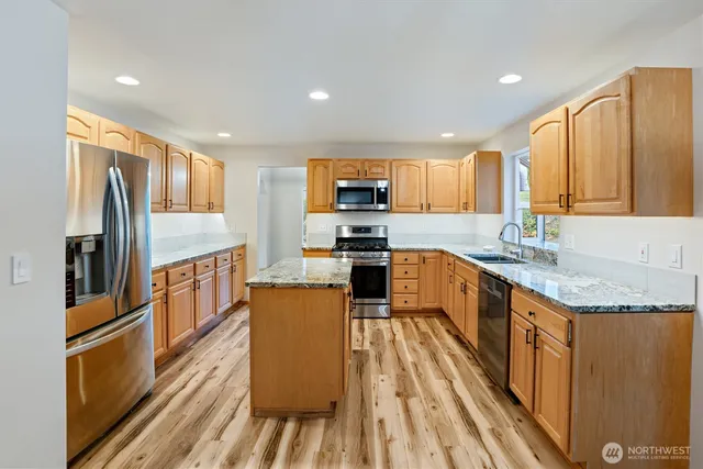 a kitchen with stainless steel appliances granite countertop a refrigerator a stove top oven a sink and dishwasher