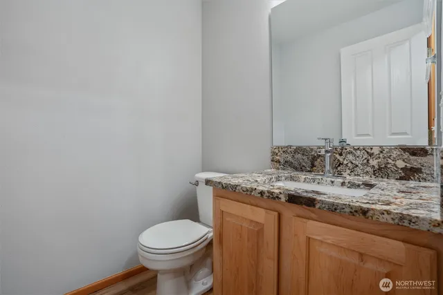 a bathroom with a granite countertop toilet and a sink