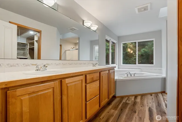 a spacious bathroom with a tub sink and mirror