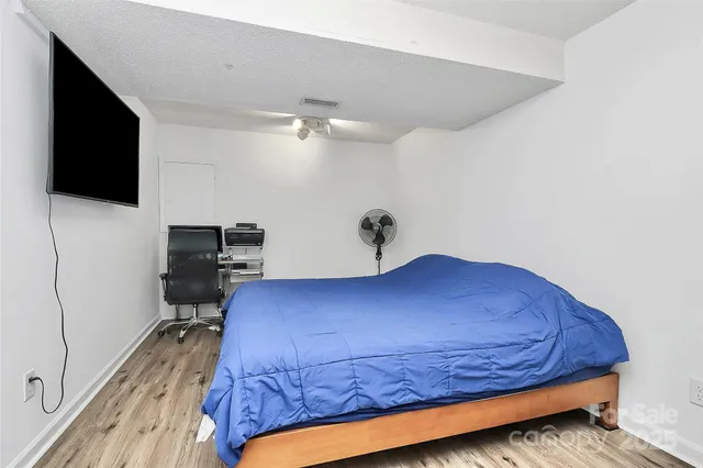 a bedroom with a bed and a flat tv screen on wall