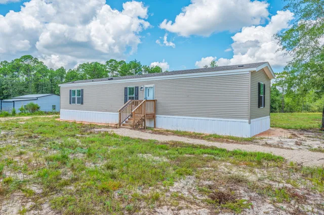 a front view of house with yard and trees in the background