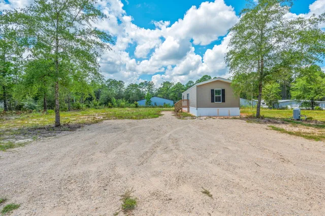 a view of a house with a yard and large trees