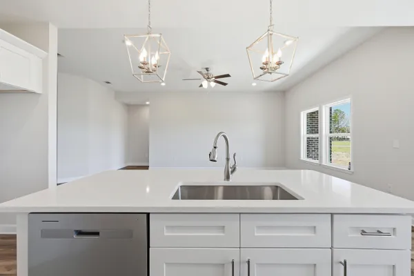 a kitchen with a sink a chandelier stainless steel appliances cabinets and a chandelier