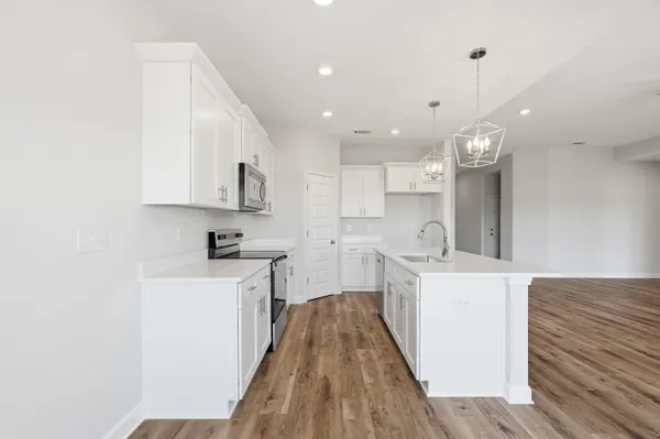 a large kitchen with stainless steel appliances kitchen island granite countertop a sink a stove and a wooden floors