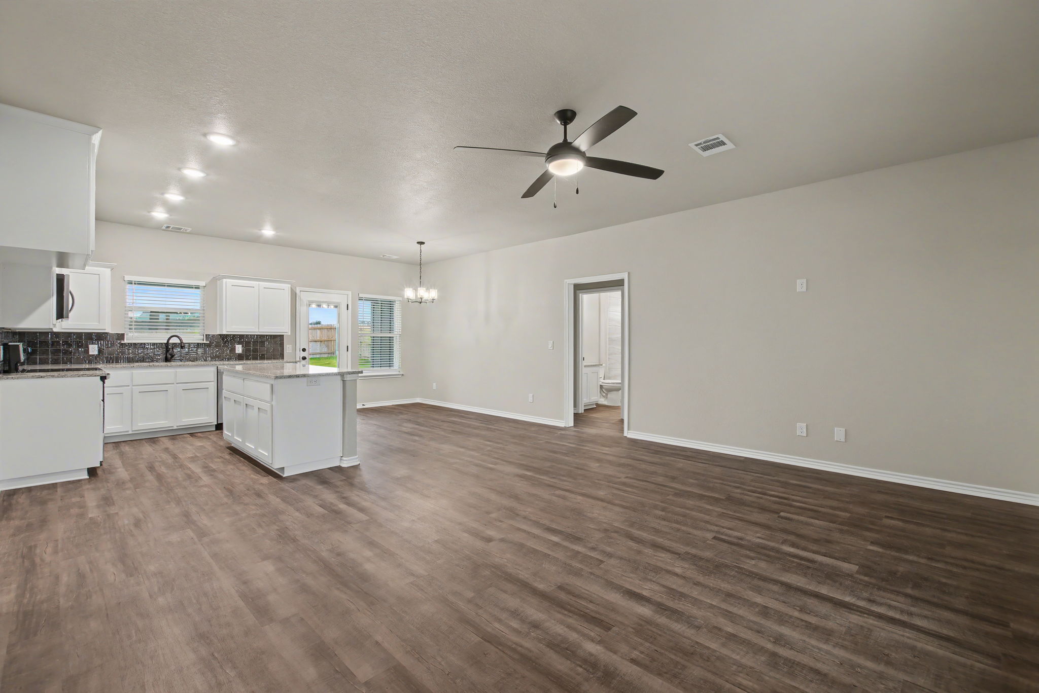 206 Water Wl Road Burnet, TX 78611 - Photo 3 of 25 Rich wood-look flooring stretches across a versatile living area connected to the modern kitchen.
