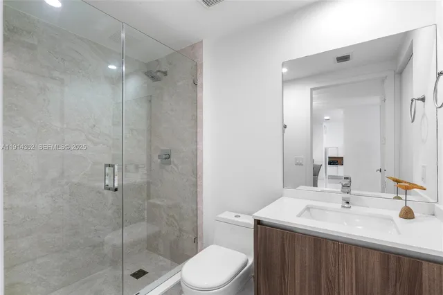 a bathroom with a sink toilet vanity and shower