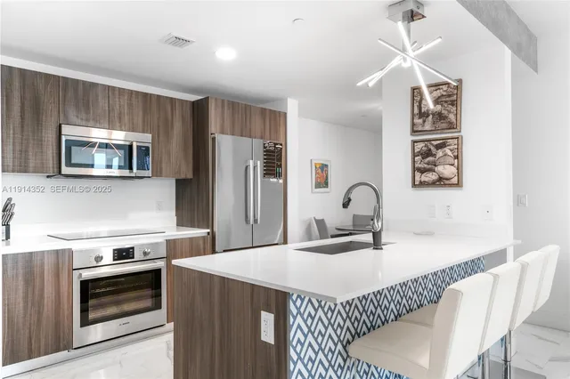 a kitchen with stainless steel appliances granite countertop a stove a sink dishwasher a refrigerator and a microwave