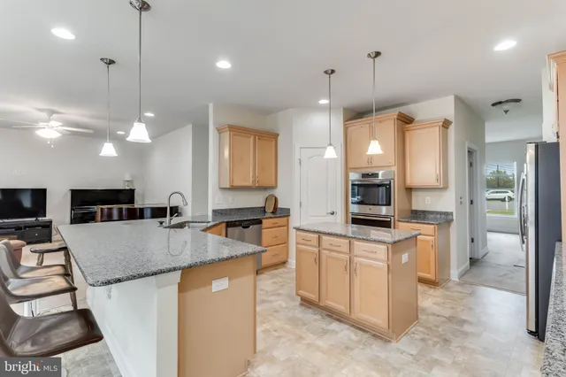 a large kitchen with kitchen island a large counter top space a sink a refrigerator and cabinets