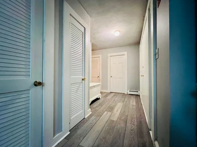 a view of a hallway with wooden floor and a bathroom