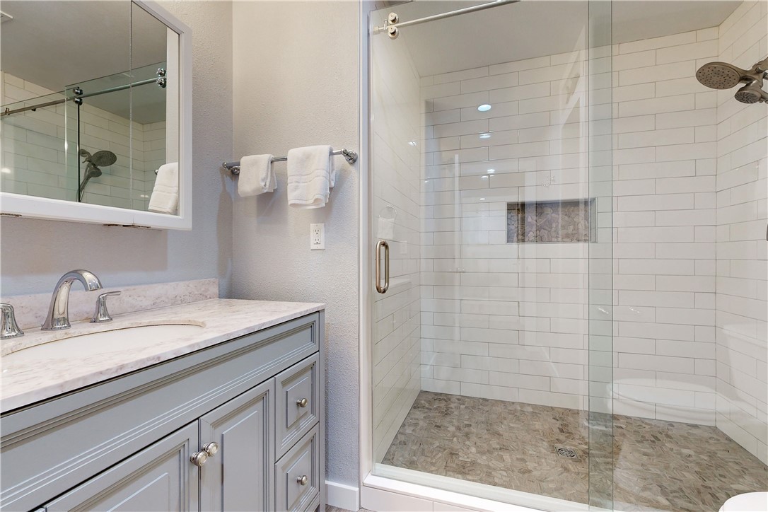 370-374 Copano Ridge Road Rockport, TX 78382 - Photo 13 of 40 a bathroom with a granite countertop sink a mirror and shower