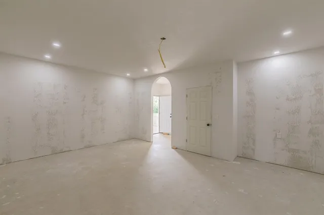 an empty room with an entryway and chandelier fan