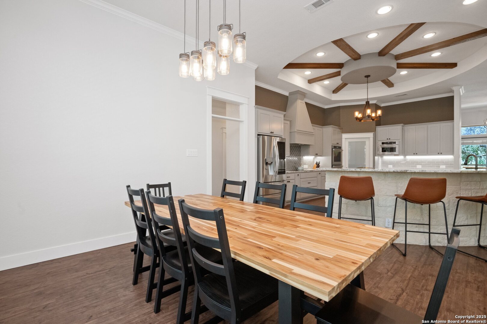10015 Kopplin Road New Braunfels, TX 78132 - Photo 14 of 38 a dining room with wooden floor a chandelier a wooden table and chairs