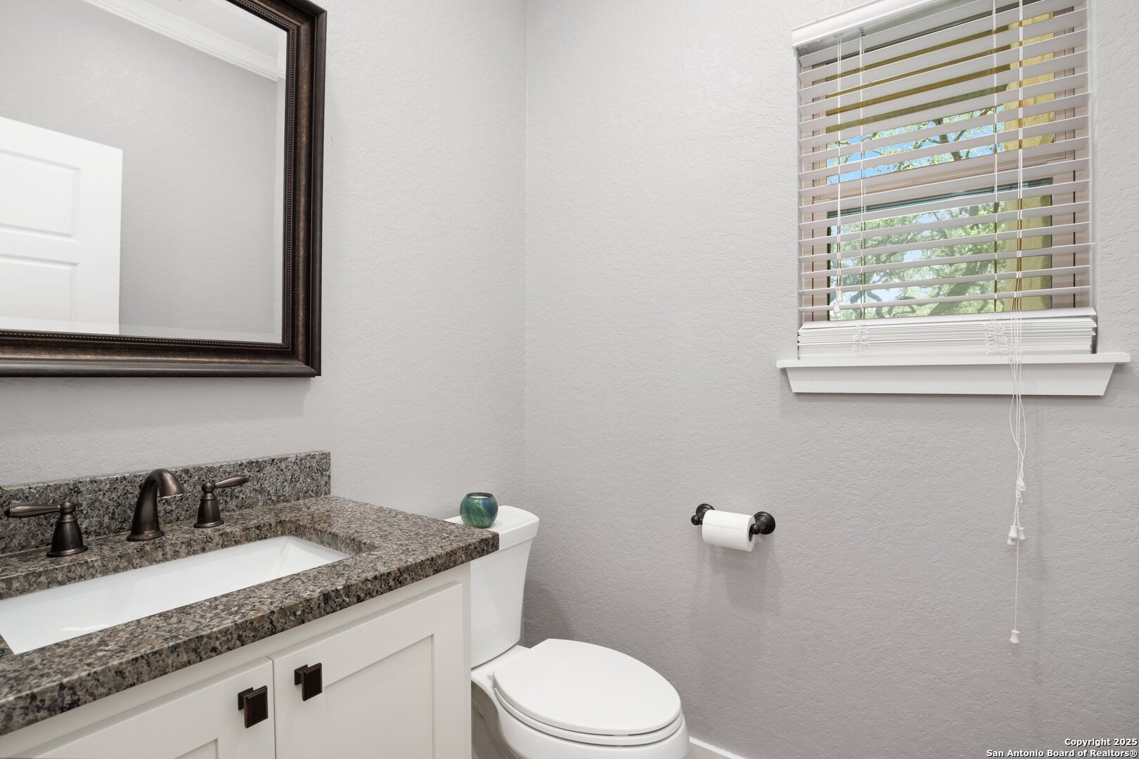 10015 Kopplin Road New Braunfels, TX 78132 - Photo 24 of 38 a bathroom with a granite countertop sink toilet and mirror