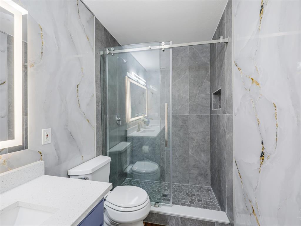 1716 East Parker Road Plano, TX 75074 - Photo 22 of 25 Contemporary bathroom featuring a walk-in shower with clear glass enclosure and hexagonal floor tiles