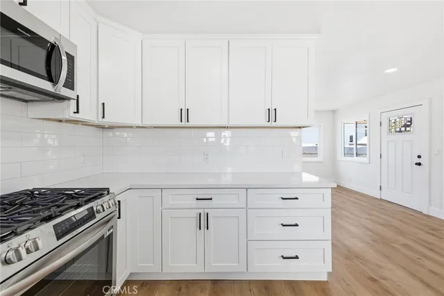 a kitchen with white cabinets and appliances