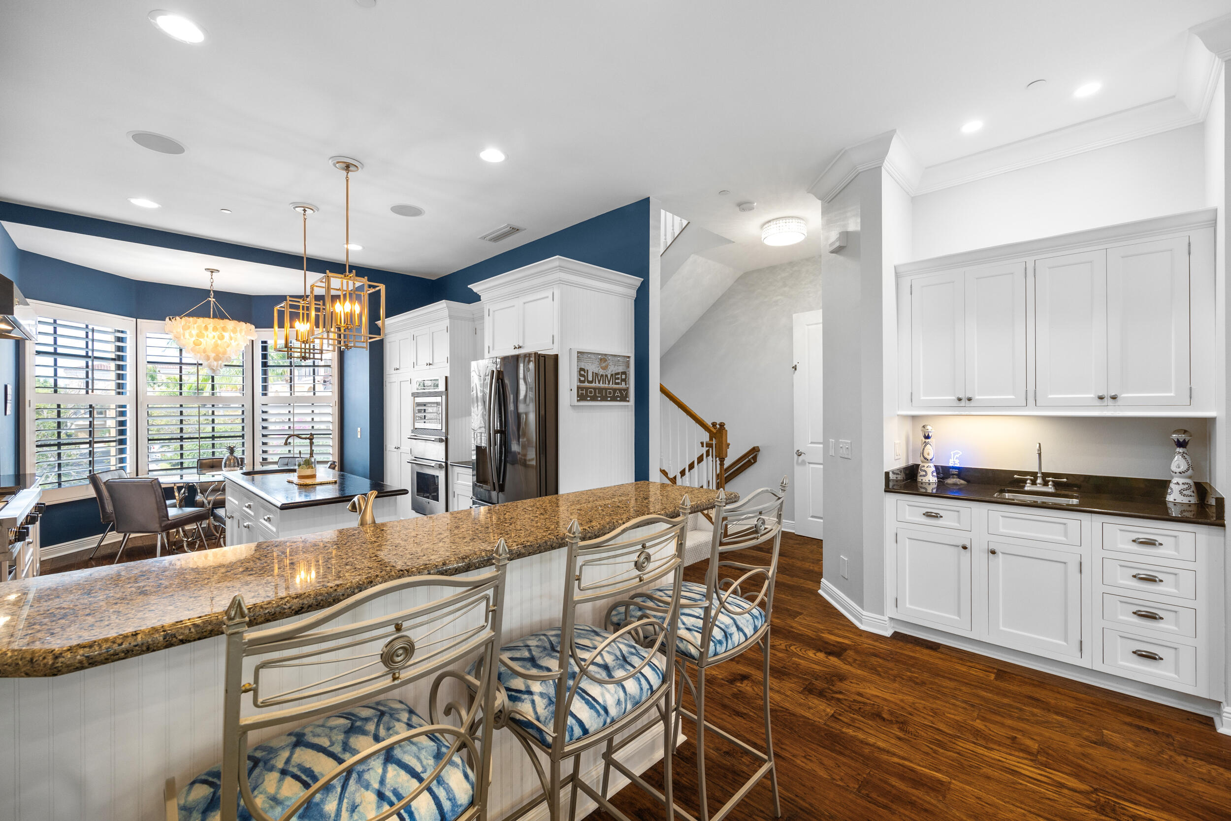 405 Del Sol Circle Tequesta, FL 33469 - Photo 12 of 53 a open kitchen with granite countertop a stove a sink a dining table and chairs with wooden floor