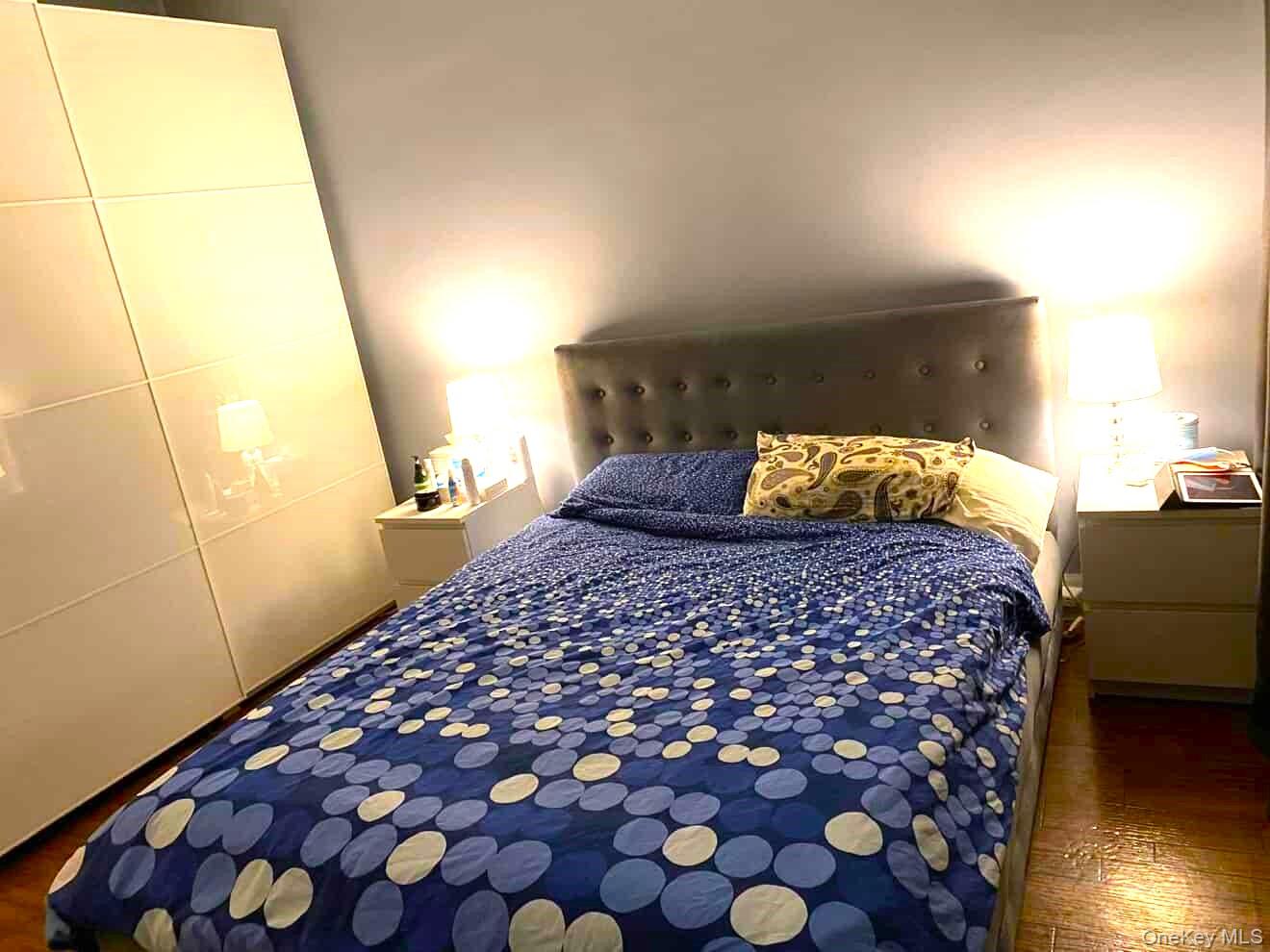 70-18 68th Street Queens, NY 11385 - Photo 10 of 12 a bedroom with a large bed and a wooden floor