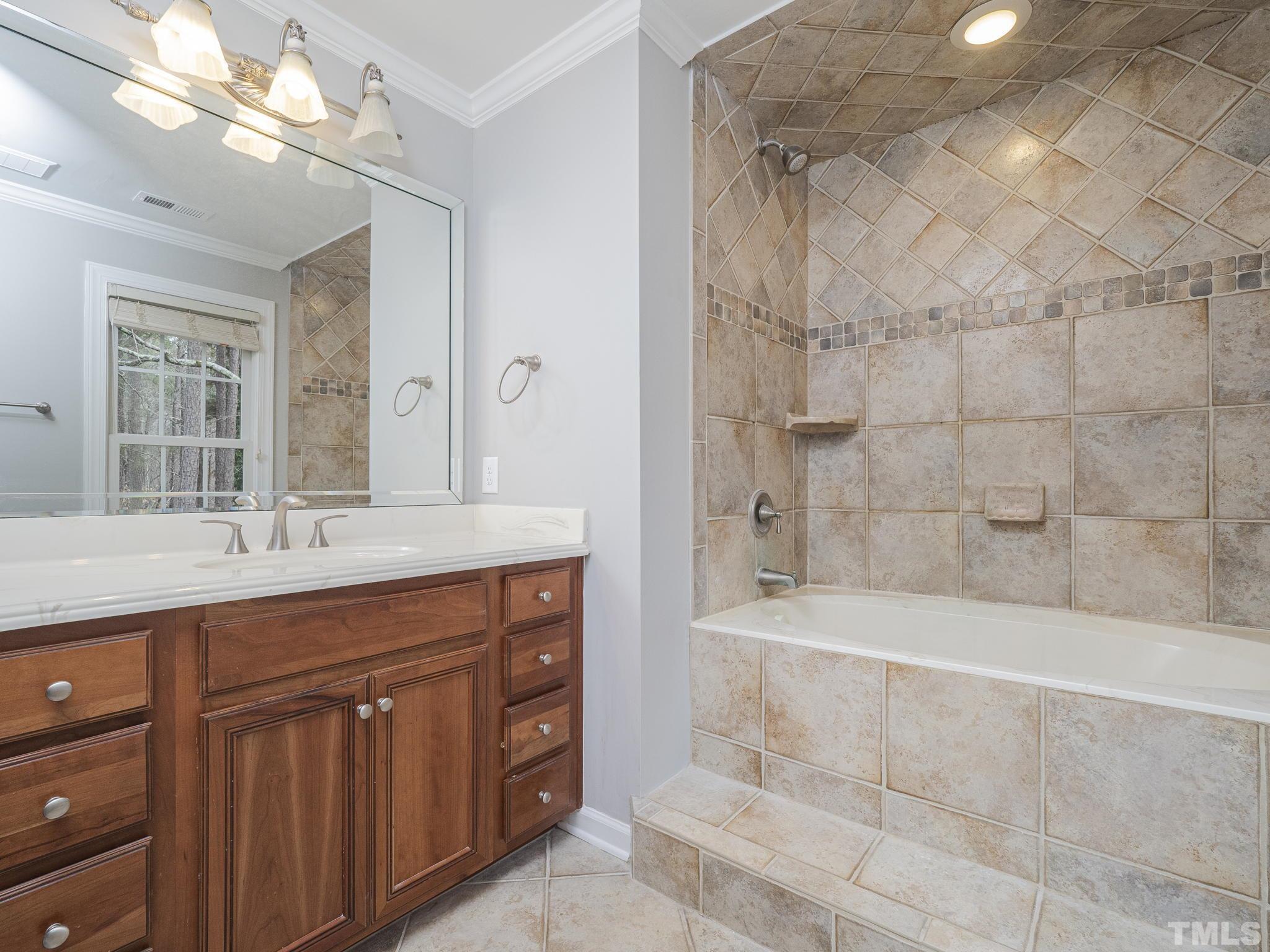 9408 Barton Creek Road Raleigh, NC 27615 - Photo 18 of 20 a bathroom with a bathtub a double vanity sink and mirror