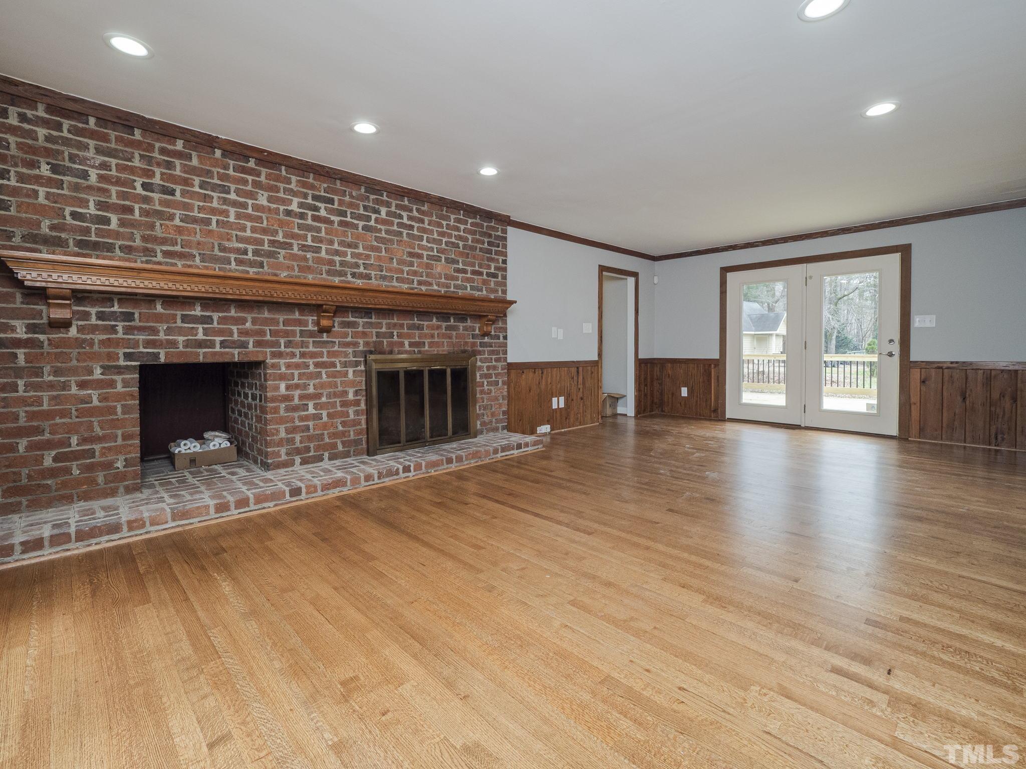 9408 Barton Creek Road Raleigh, NC 27615 - Photo 10 of 20 an empty room with wooden floor fireplace and windows