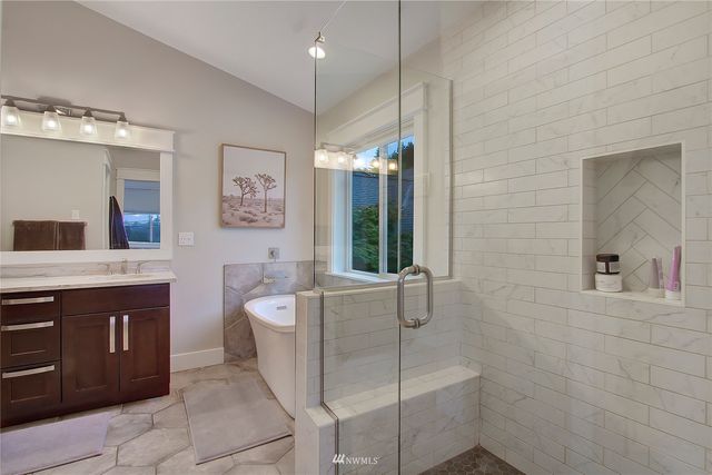 a spacious bathroom with a tub sink and mirror
