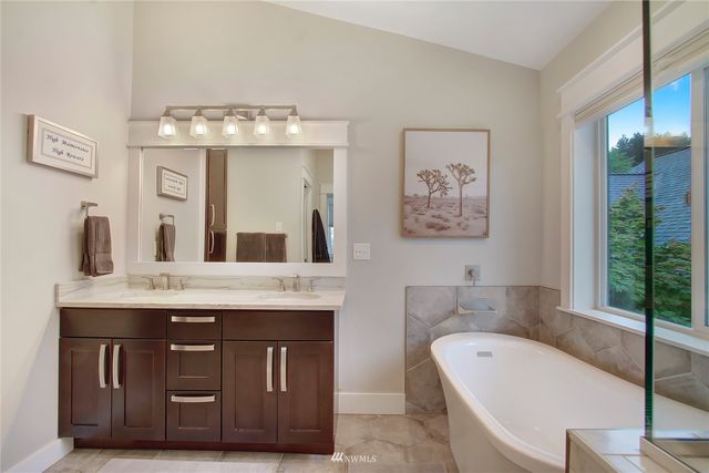 a bathroom with a tub a double vanity sink and a large mirror