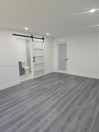 a view of an empty room with wooden floor closet and windows