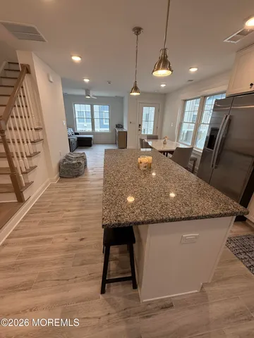 a kitchen with stainless steel appliances granite countertop a table chairs refrigerator and microwave