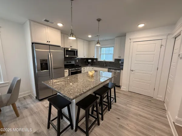 a kitchen with stainless steel appliances granite countertop a refrigerator a stove top oven a sink island and a refrigerator