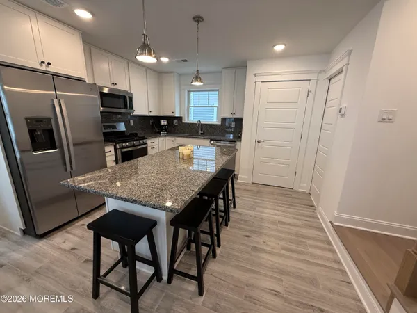 a kitchen with stainless steel appliances kitchen island granite countertop a refrigerator and microwave