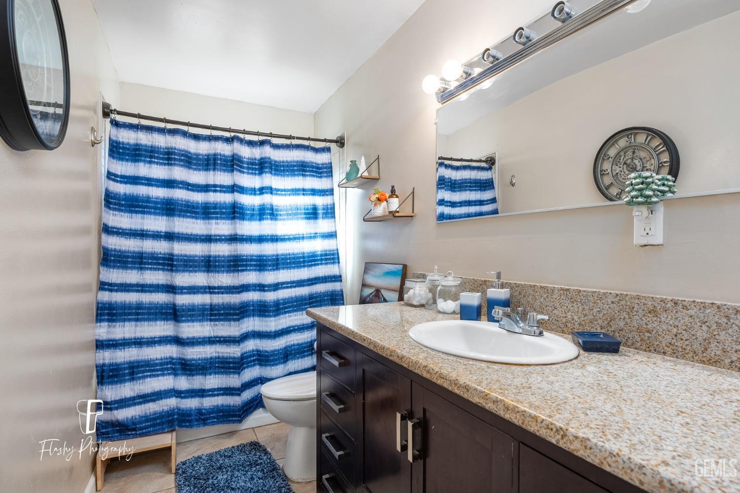 Undisclosed Address Bakersfield, CA 93304 - Photo 19 of 28 a bathroom with a granite countertop sink a mirror and a shower