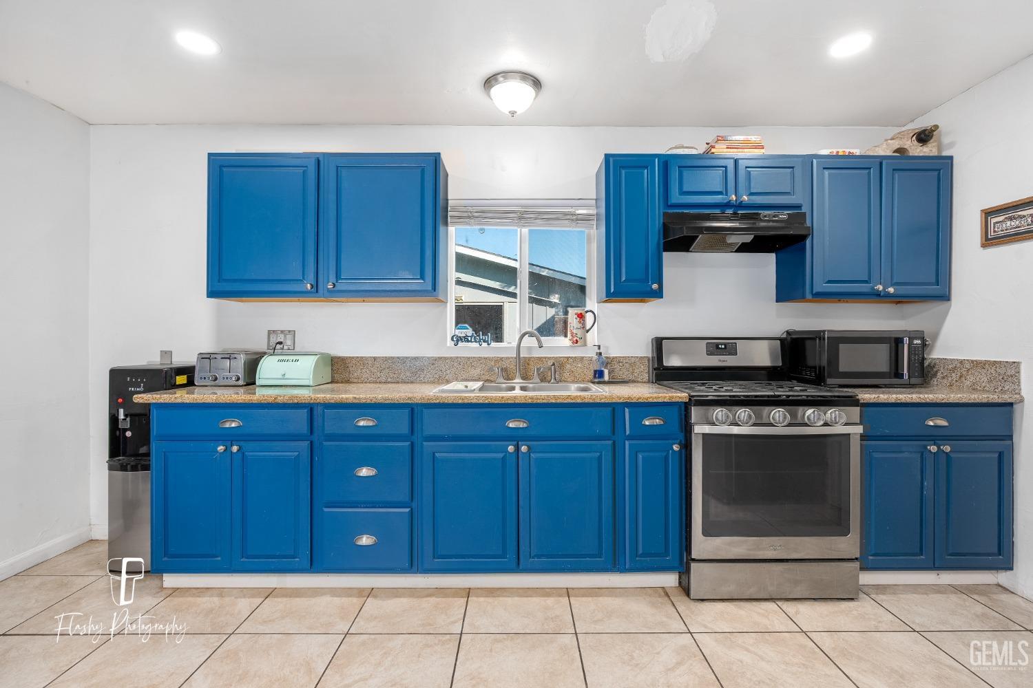 Undisclosed Address Bakersfield, CA 93304 - Photo 10 of 28 a kitchen with stainless steel appliances granite countertop wooden cabinets a stove a sink and a window