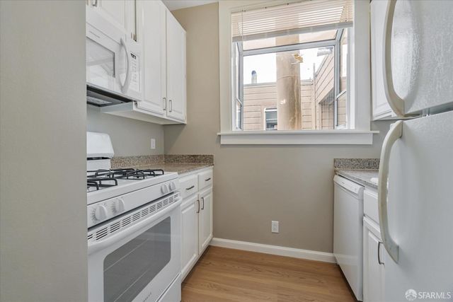 a kitchen with granite countertop cabinets appliances and a wooden floor