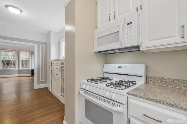 an empty room with wooden floor cabinet and windows