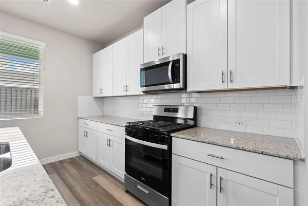 a kitchen with granite countertop white cabinets stainless steel appliances and a window