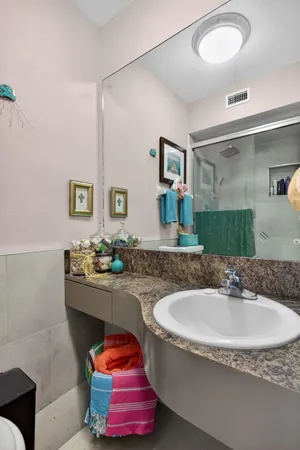 a bathroom with a granite countertop sink a mirror and shower