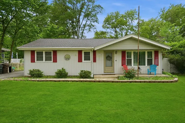a front view of a house with a garden and trees
