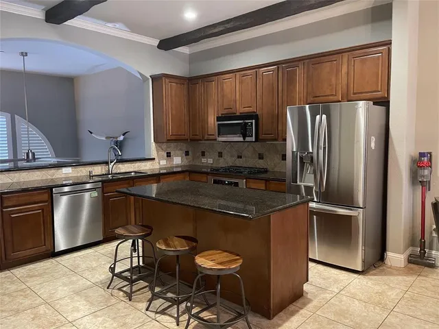 a kitchen with kitchen island a counter top space cabinets and stainless steel appliances
