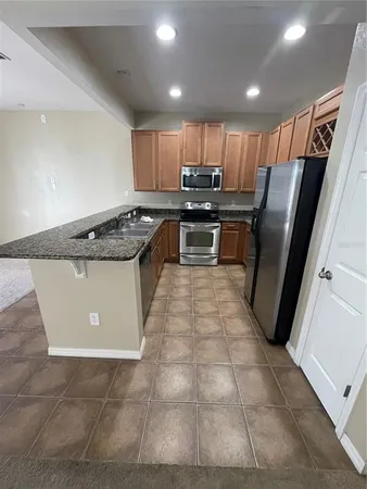 a kitchen with stainless steel appliances granite countertop a sink a stove a microwave and a refrigerator