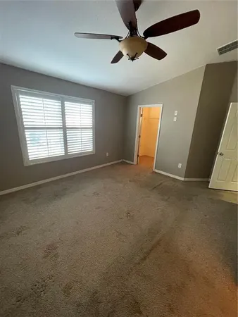 an empty room with windows and fan
