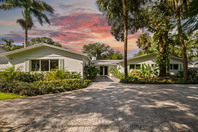 a front view of a house with a garden and trees